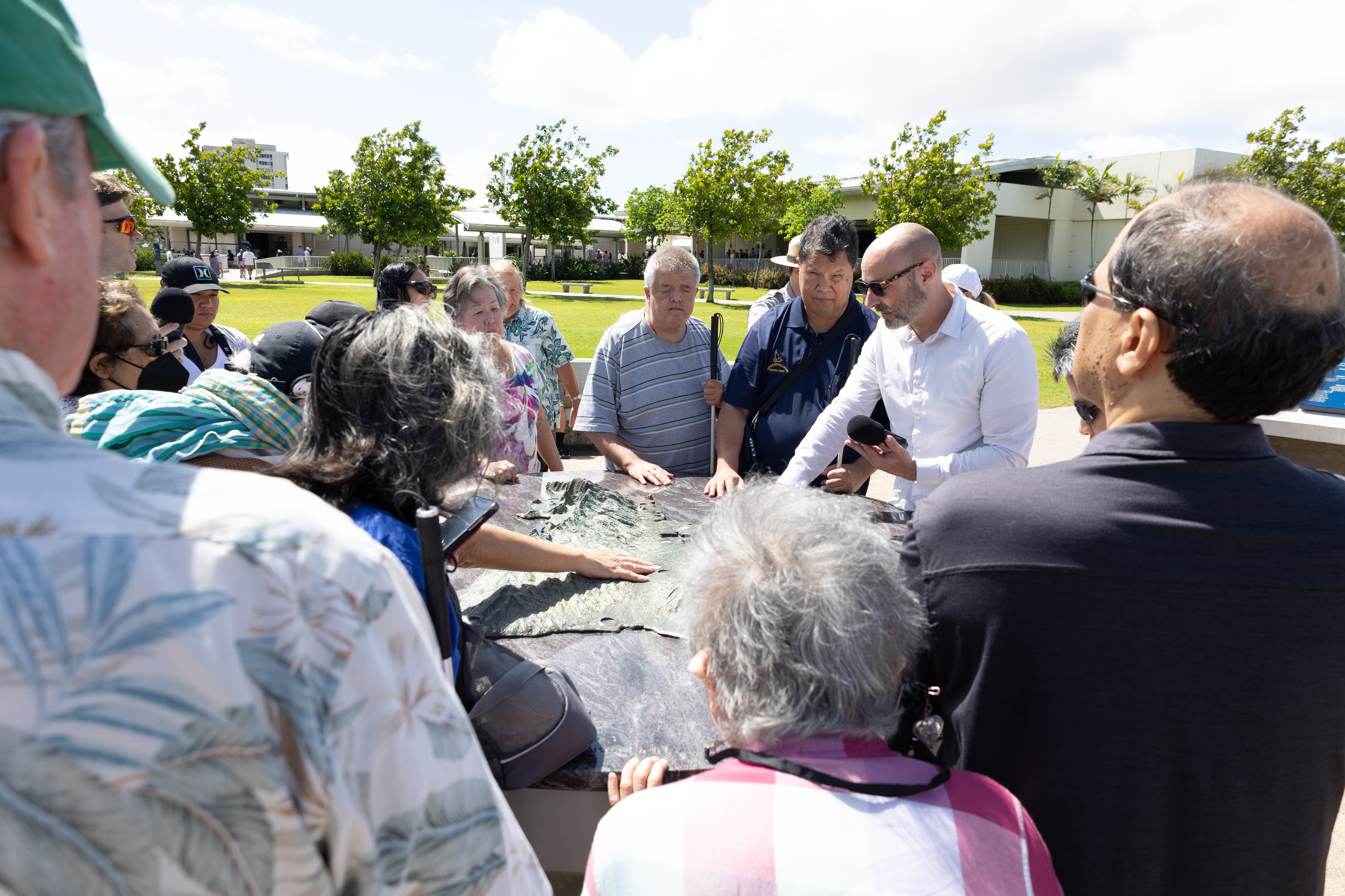 Photo of Testing Audio Description: Dr. Jordan Frith and research participants listening to our NFC tag placed on an outdoor map at Pearl Harbor National Memorial (2023)