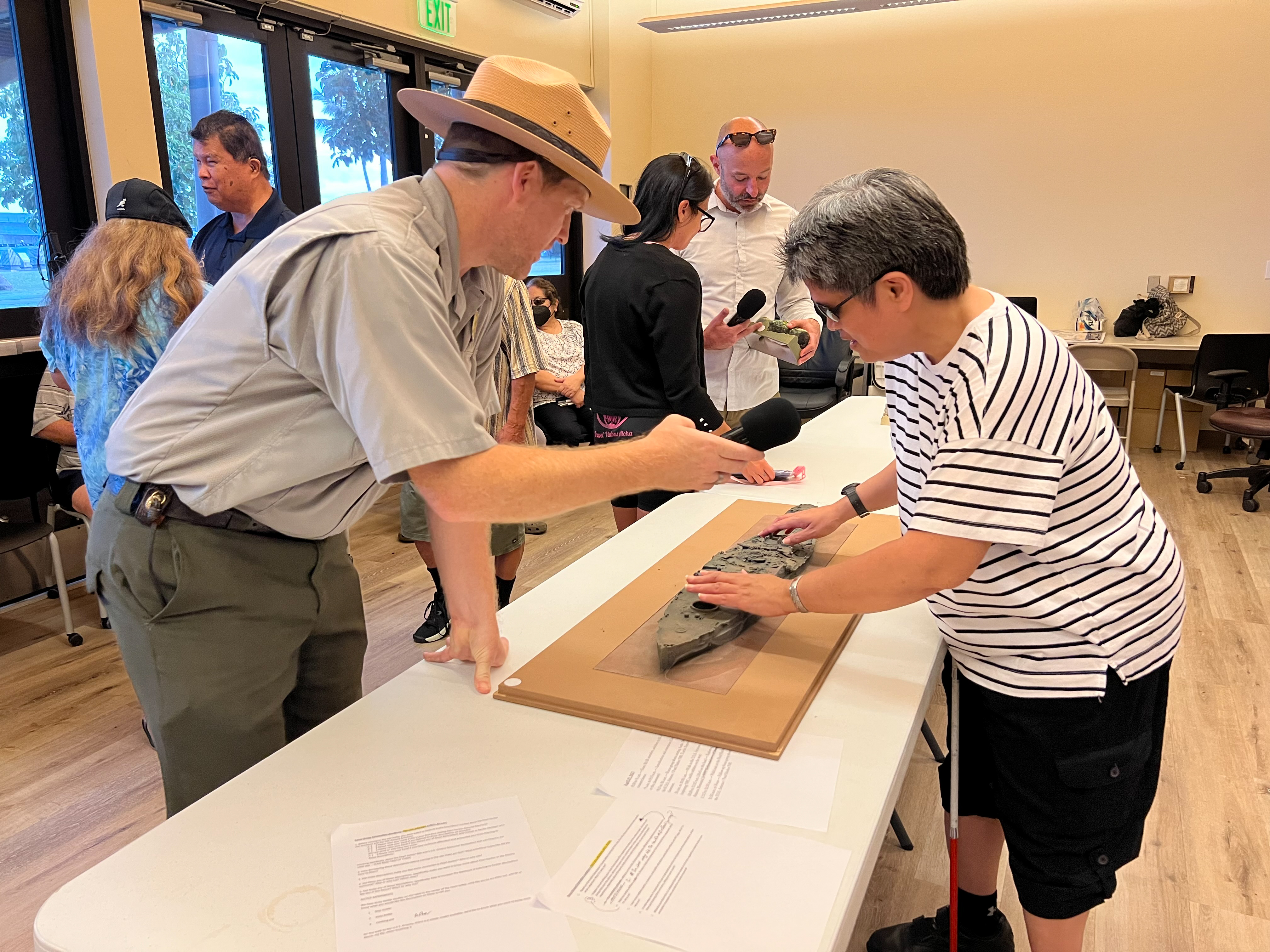 Photo of Testing Audio Description: David Kilton, Chief of Interpretation at Pearl Harbor National Memorial, shares a tactile model of the U.S.S. Arizona with research participants (2023)